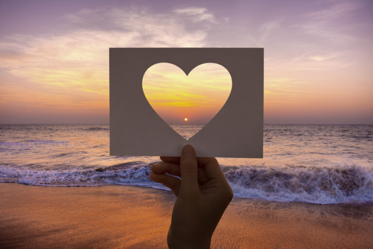 Sunset though a cut-out heart on a paper, follow your heart